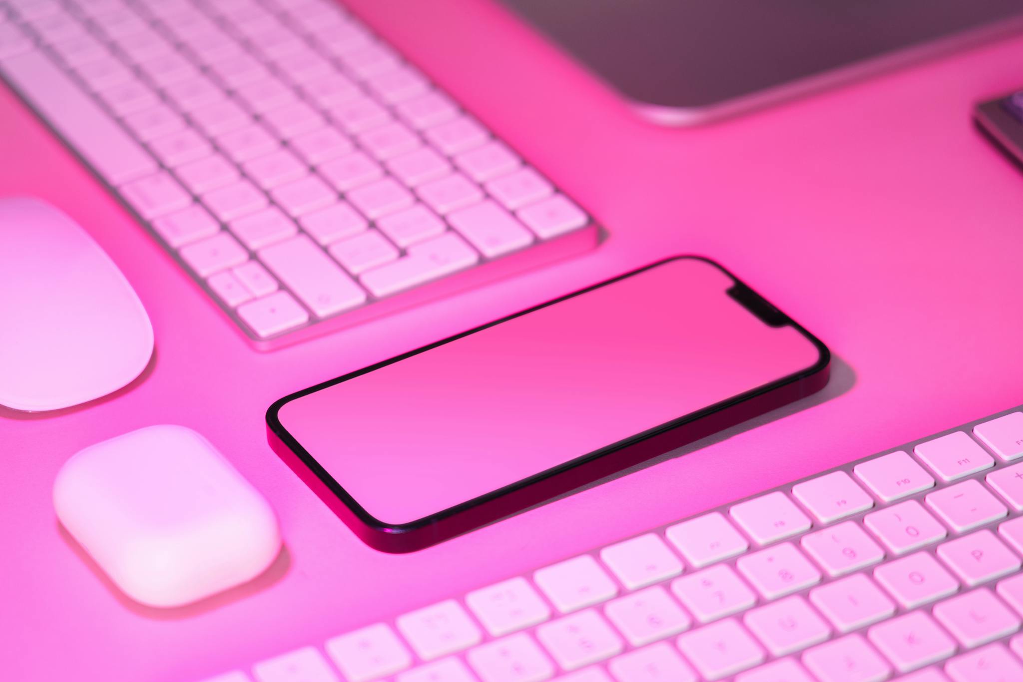 Modern pink-themed workspace featuring a smartphone, keyboard, and mouse. Ideal for tech and business concepts.