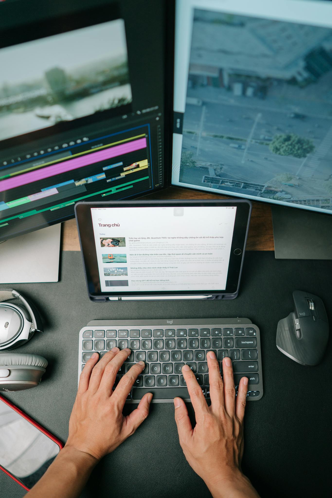 Person typing on keyboard in modern workspace with multiple screens displaying content.